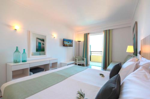 a white bedroom with a large bed and a desk at Samaina Inn in Karlovasi