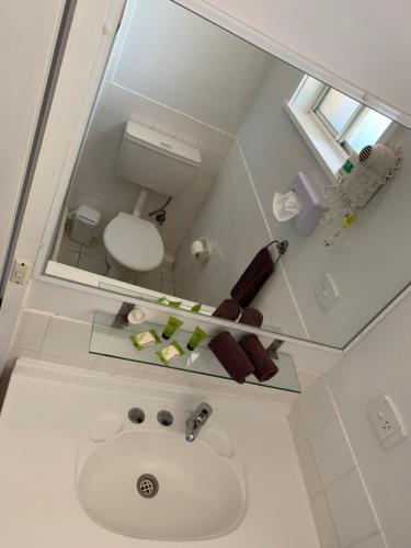 a bathroom with a sink, mirror, and soap dispenser at Orana Windmill Motel in Gilgandra