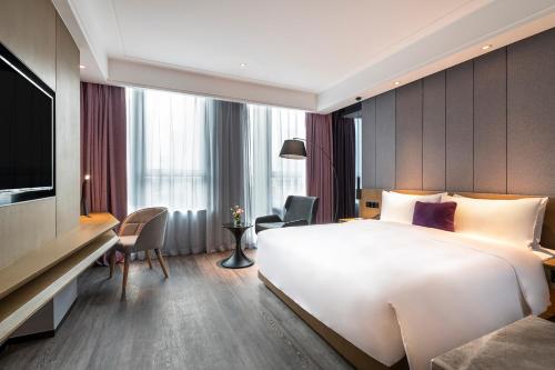 a hotel room with a large bed and a television at Mercure Kunshan Hi Tech Zone in Kunshan