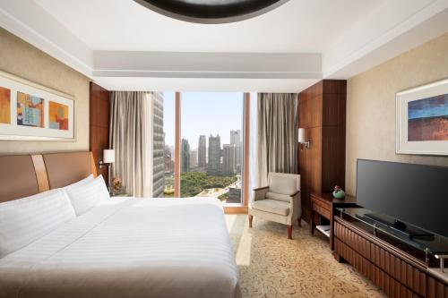 a hotel room with a bed and a television at Pudong Shangri-La Shanghai - With a sweeping view of the Pearl Tower and the historic Bund skyline in Shanghai