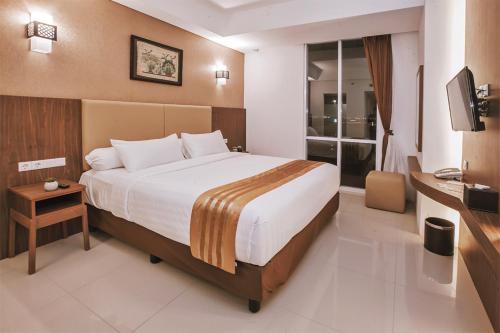 a hotel room with a large bed and a television at The Azana Hotel Airport Semarang in Semarang