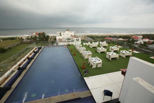Blick auf einen Pool mit Tischen und Stühlen in der Unterkunft The Bentley Seaside Boutique Hotel in Chennai