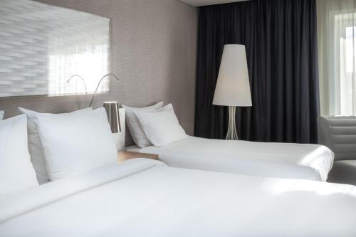 two white beds in a hotel room with a lamp at Radisson Blu Scandinavia Hotel Aarhus in Aarhus
