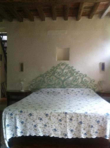 - une chambre dotée d'un lit avec un couvre-lit floral dans l'établissement Antico Rustico fra vigneti e uliveti, à Corsanico-Bargecchia