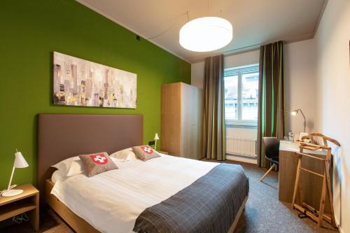 a bedroom with a bed and a green wall at Hotel Bären am Bundesplatz in Bern