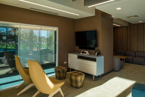 a living room with a tv and chairs and a couch at Elite Athlete Centre and Hotel in Loughborough