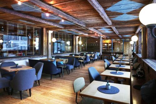 JUFA Alpenhotel Saalbach في سالباخ هينترغليم: مطعم بسقوف خشبية وطاولات وكراسي