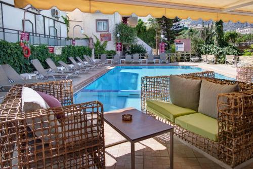 a pool with chairs and a couch and a table at Le Palme in Malia