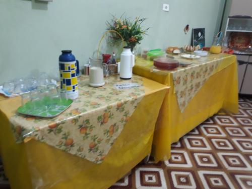 twee gele tafels met eten erop bij Hotel Shangri-la in Três Corações