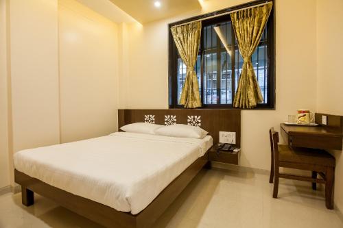 a bedroom with a bed and a desk and a window at City Guest House - Dadar in Mumbai