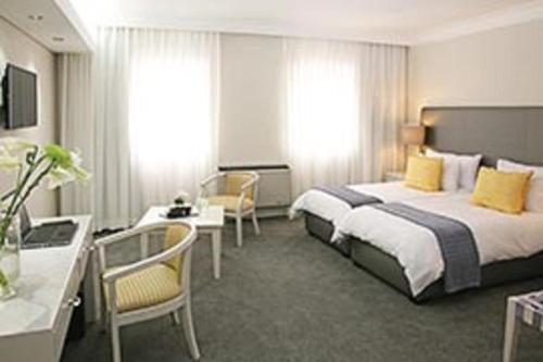 Habitación de hotel con cama y escritorio en Hollow on the Square City Hotel, en Ciudad del Cabo