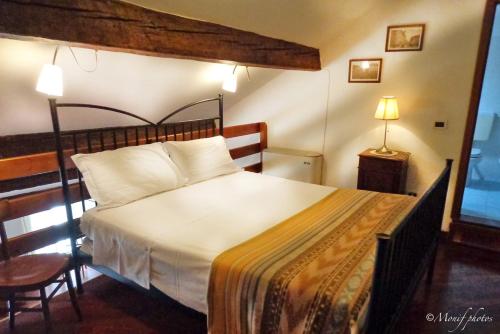 een slaapkamer met een groot bed met witte lakens en kussens bij Locanda Della Biscia in Ferrara