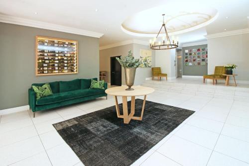 a living room with a green couch and a table at Hollow on the Square City Hotel in Cape Town