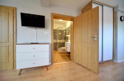 a bathroom with a dresser with a tv on the wall at Apartamenty EverySky - Wilcza 3F-2 in Karpacz