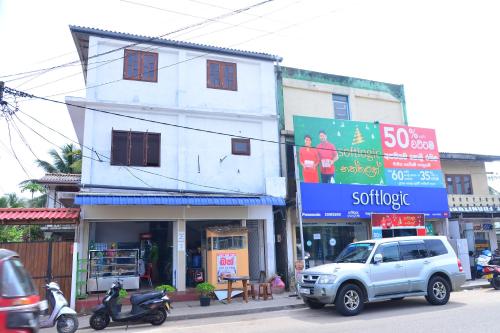 a white building with a sign on the side of a street at Roshan's Guest House in Hikkaduwa
