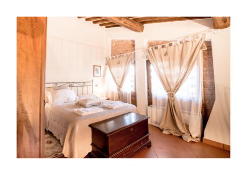 a bedroom with a bed and a table and curtains at Casale Podernovo in Terricciola