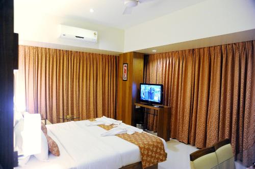 a hotel room with a bed and a television at Hotel Sea Fans in Ratnagiri