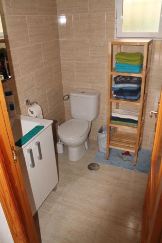 a bathroom with a toilet and a shelf with towels at Casa Alegria Mazarron in Mazarrón