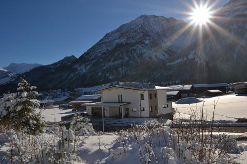 a building in the snow with a mountain in the background at fewo kramer in Heiterwang