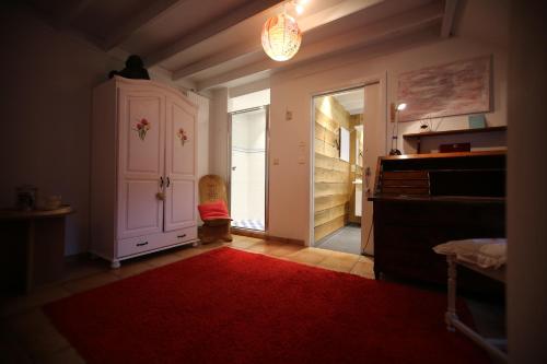 a room with a red rug and a closet with a piano at Barsy 34 in Havelange