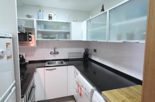 a kitchen with white cabinets and a black counter top at Espacioso ap en Gessa in Gessa