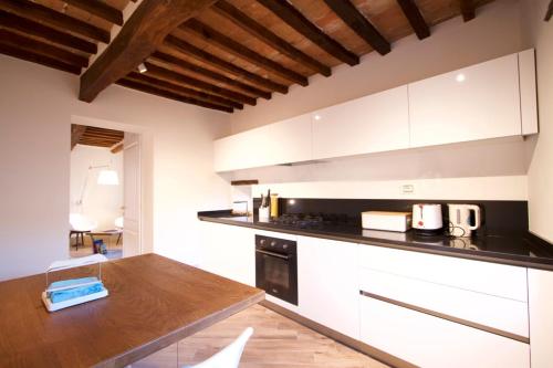 a kitchen with white cabinets and a wooden counter top at Torre appartamento con vista in Monticchiello