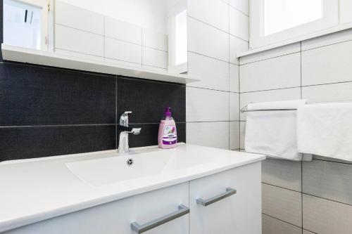 a white bathroom with a sink and a soap bottle at Stylish Centre Apartments in Zadar