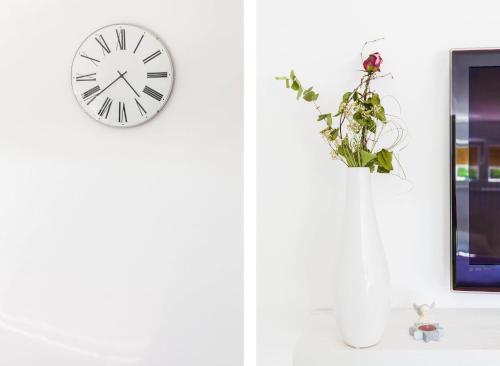 a clock on a wall next to a vase with a plant at Stylish Centre Apartments in Zadar