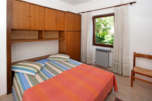 sypialnia z łóżkiem, drewnianymi szafkami i oknem w obiekcie Apartments Mladenka w Poreču
