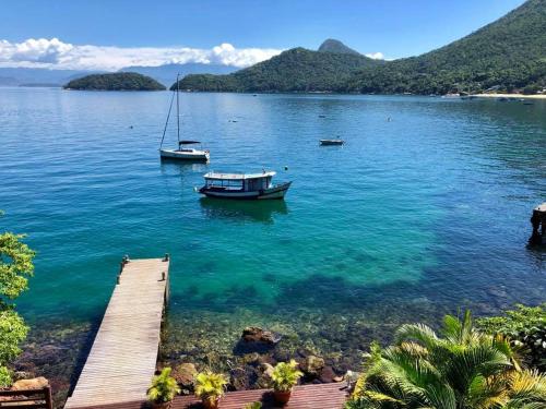 a boat sitting on the water next to a dock at Pousada Cruzoé in Praia de Araçatiba