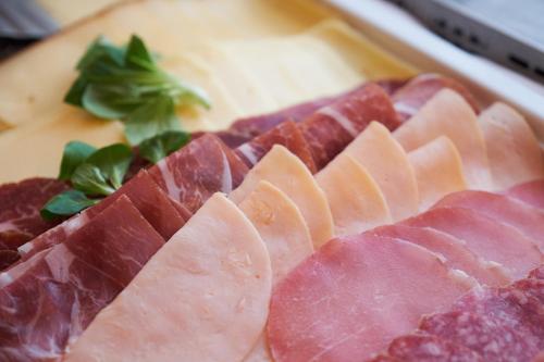 a bunch of ham on a wooden cutting board at Apartment Travego II in Osijek