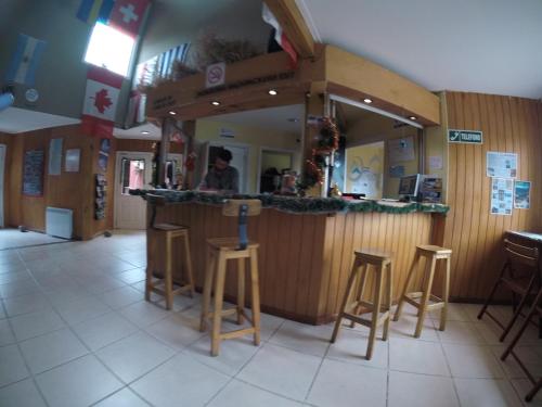 a bar in a restaurant with stools in the middle at Hostel del Glaciar Pioneros in El Calafate