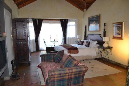 a bedroom with a bed and a couch and a chair at Fox & Squirrel in Dullstroom