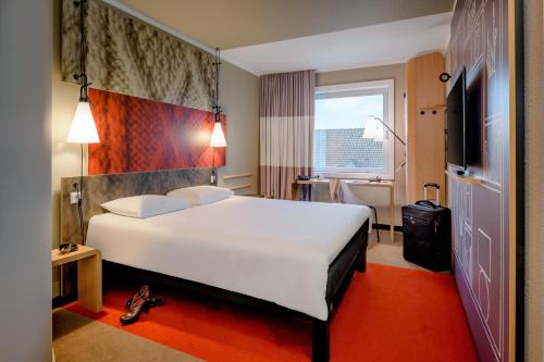 a hotel room with a large white bed and a window at Ibis Münster City in Münster
