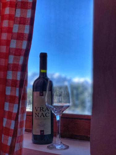 a bottle of wine and a glass sitting next to a window at Apartments Radingturs in Žabljak