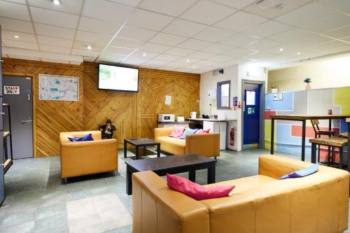 a waiting room with couches and tables and a television at St Christopher's Inn Shepherd's Bush in London