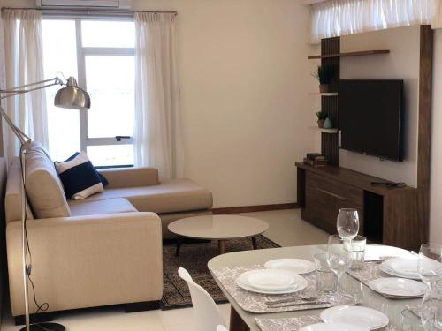 a living room with a couch and a tv at Centro de Asunción Nuevo Apartamento, Cómodo, Seguro, Piscina, Gimnasio y Parking in Asuncion