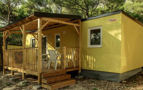 a small yellow tiny house with a deck at Mobile Homes Camp Pineta - Adriatic Kampovi in Fažana