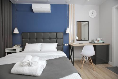 a bedroom with a blue wall and a bed with two towels at Hotel Sova in Krasnoyarsk