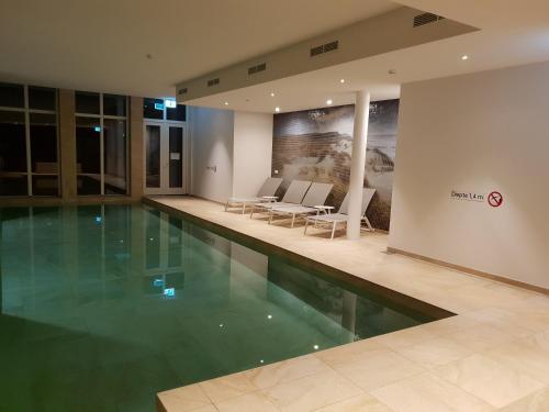 a swimming pool in a building with tables and chairs at Penthouse Windkracht 10 aan het strand van Cadzand in Cadzand