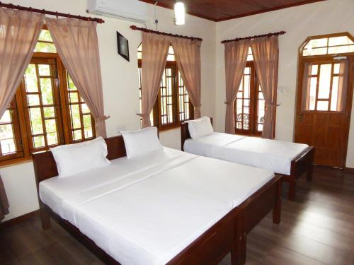 two beds in a room with windows at Riviera Resort in Batticaloa