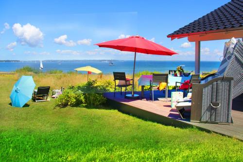Una terraza con sillas y una sombrilla en la playa. en Ferienhaus Skagen, en Steinbergkirche