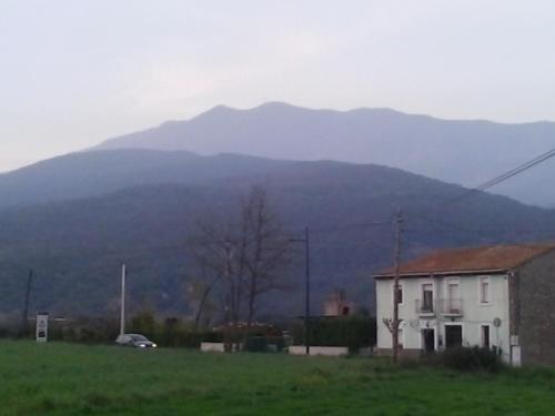 a house in a field with a mountain in the background at Casa Montseny con piscina,bosque in Sant Pere de Vilamajor