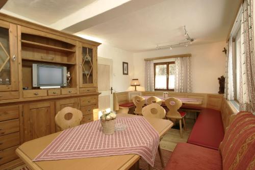 Una sala de estar con una mesa y sillas y un televisor. en Ferienhaus/Chalet Schneiderhäusl, en Flachau