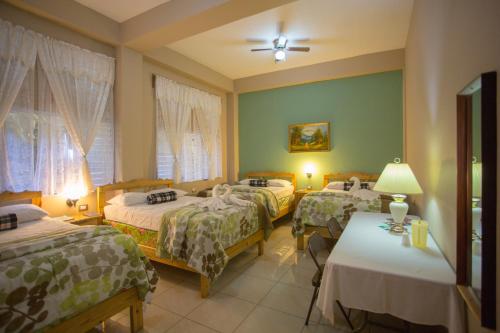 a hotel room with three beds and a table at Hotel San Jorge in Santa Rosa de Copán