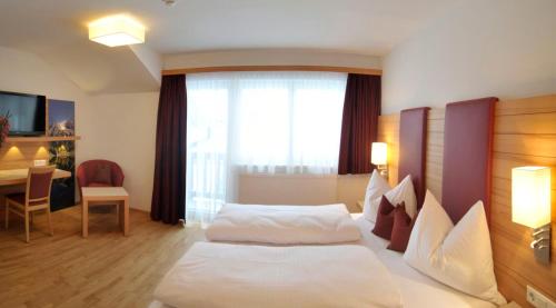 a hotel room with two white beds and a table at Hotel Sonnschupfer in Schladming