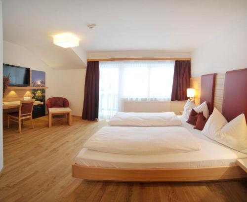 a hotel room with a large bed and a desk at Hotel Sonnschupfer in Schladming