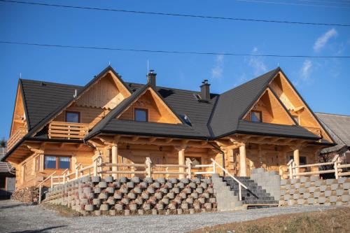 une maison en rondins avec un toit noir dans l'établissement Dwór Pan Tadeusz, à Orawka