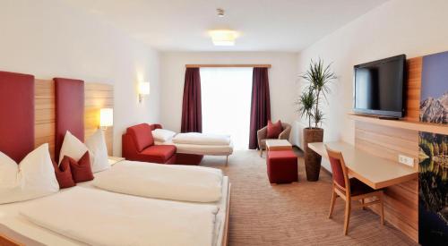 a hotel room with a couch and a tv at Hotel Sonnschupfer in Schladming