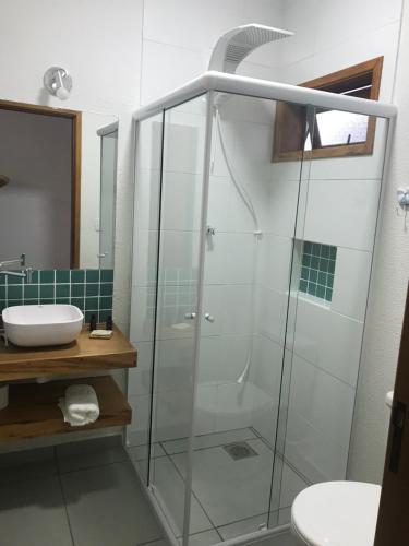 a bathroom with a glass shower and a sink at Nai'a Suites in Ubatuba